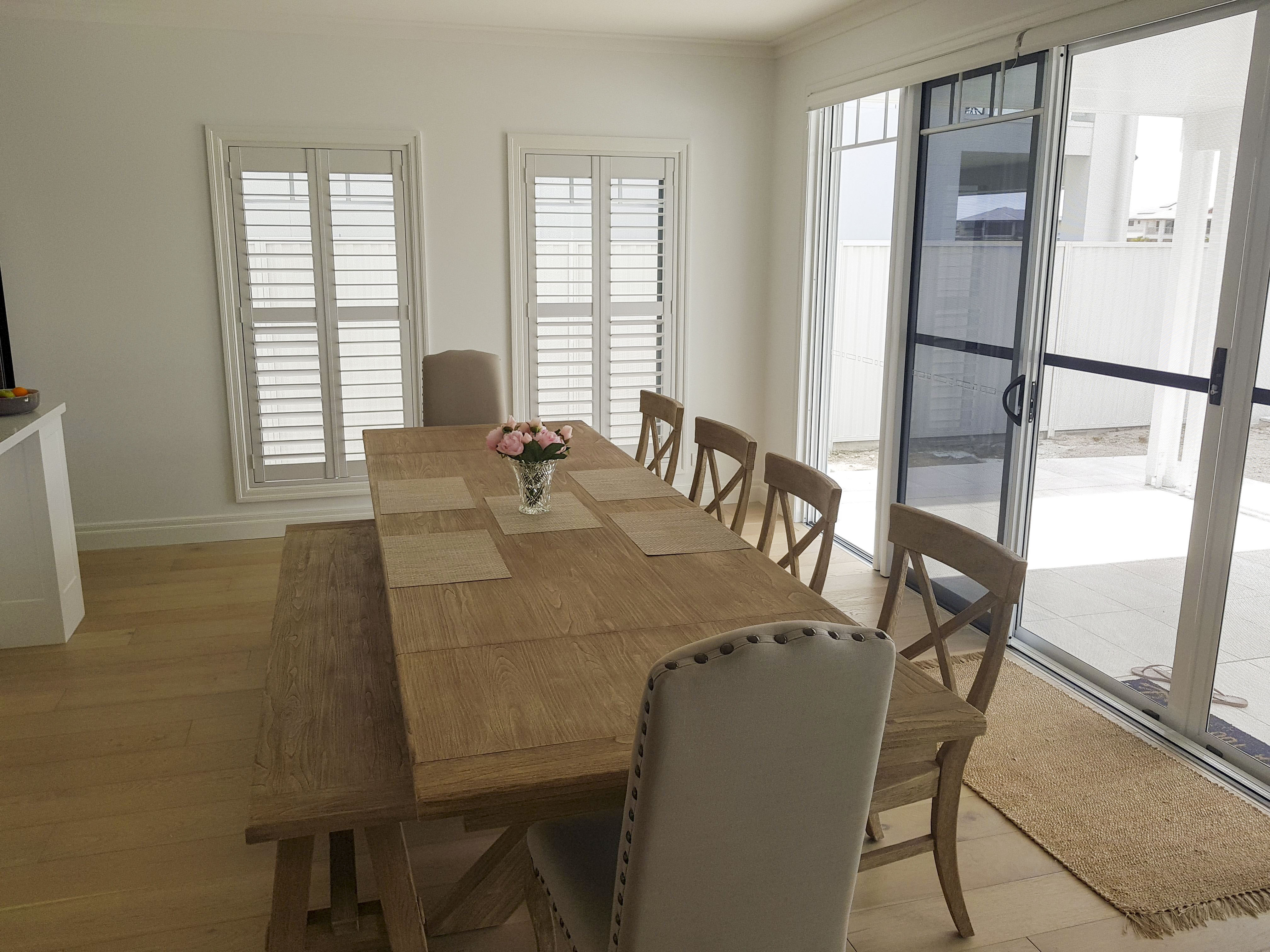 dining room with timber table grey chairs and large sliding door and shutters